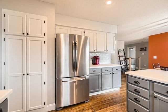 kitchen with wood finished floors, gray cabinets, freestanding refrigerator, light countertops, and backsplash