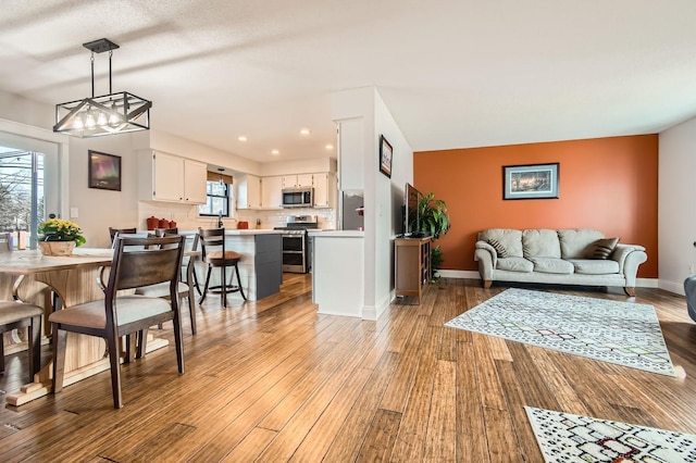 living room with a notable chandelier, recessed lighting, light wood-type flooring, and baseboards