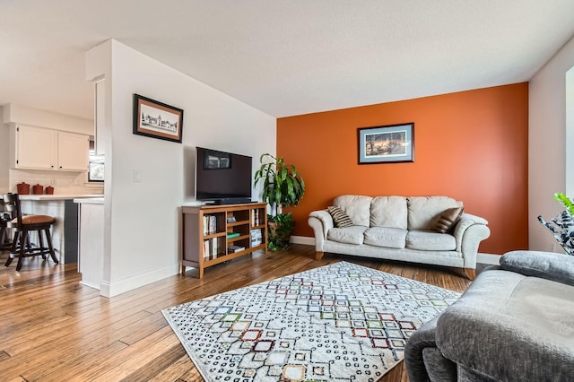 living room featuring a textured ceiling, light wood-type flooring, and baseboards