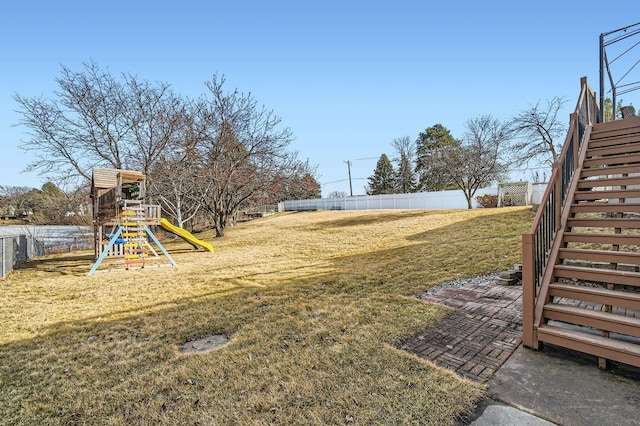 view of yard featuring stairs, a playground, and fence