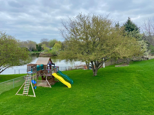 view of jungle gym with fence, a lawn, and a water view