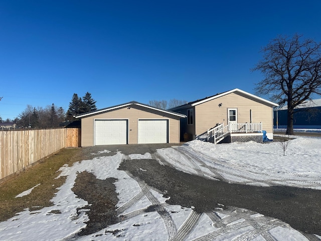 view of front of house featuring a detached garage, an outdoor structure, and fence