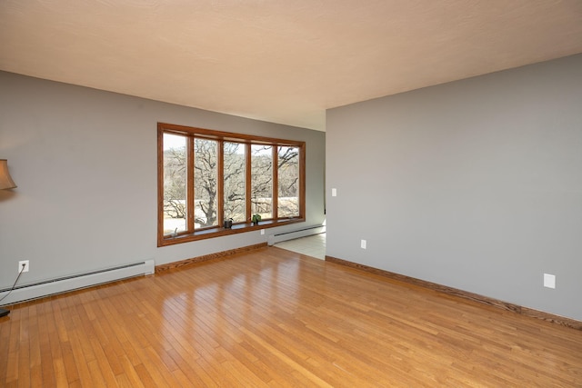 unfurnished room featuring baseboards, baseboard heating, and light wood-style flooring