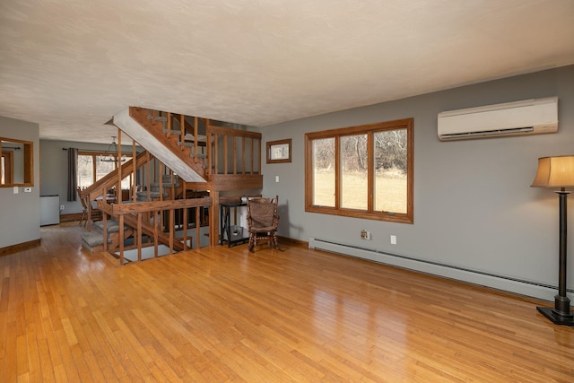 unfurnished living room with hardwood / wood-style flooring, stairs, a wall unit AC, and a baseboard radiator