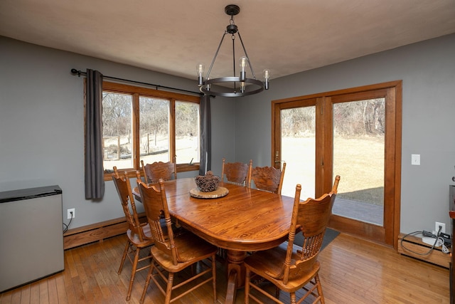 dining room featuring baseboards, an inviting chandelier, a healthy amount of sunlight, and light wood finished floors