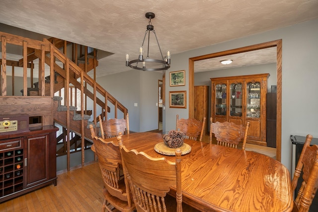 dining space with a chandelier, stairway, a textured ceiling, and hardwood / wood-style floors