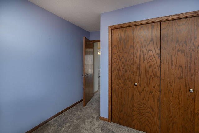 unfurnished bedroom featuring a closet, baseboards, and carpet floors