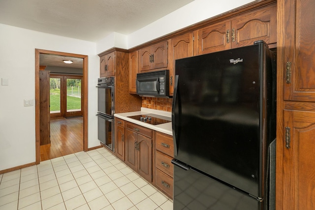 809 60th Ave SW, Rochester, MN 55902 - kitchen featuring black appliances, light countertops, backsplash, light tile patterned floors, and baseboards