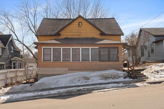 view of front of house featuring roof with shingles and fence