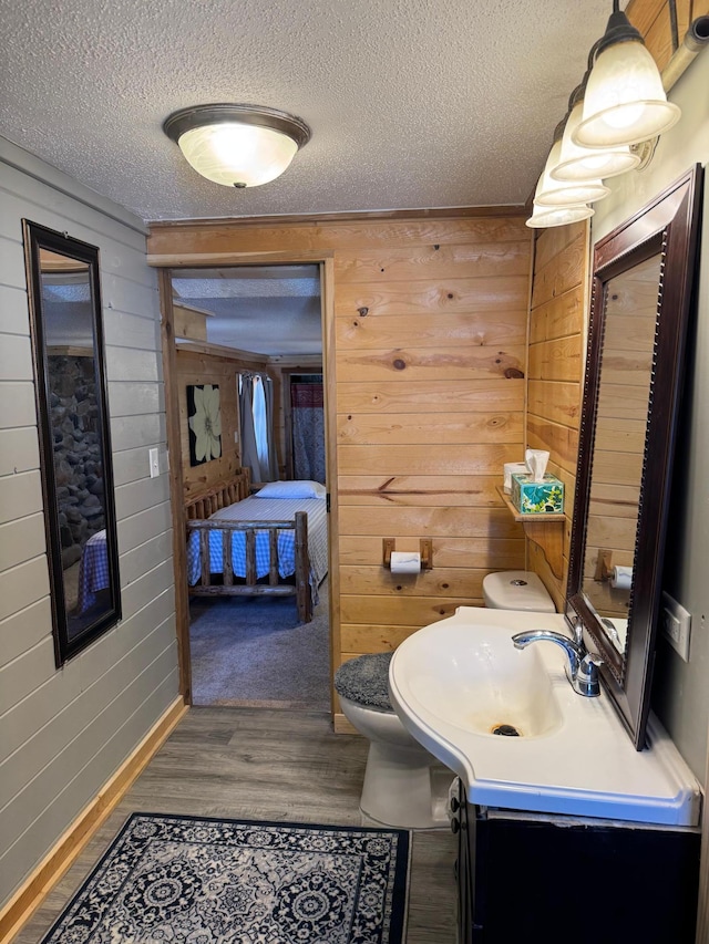 20455 326th Ave, Isle, MN 56342 - ensuite bathroom with a textured ceiling, wooden walls, wood finished floors, and toilet