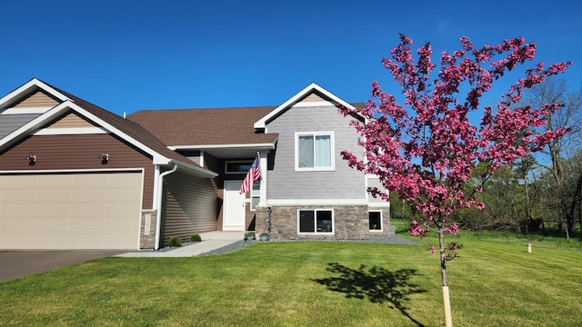 view of front of house featuring stone siding, a front yard, and an attached garage