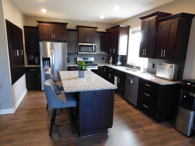 kitchen with a sink, stainless steel appliances, a kitchen island, and decorative backsplash