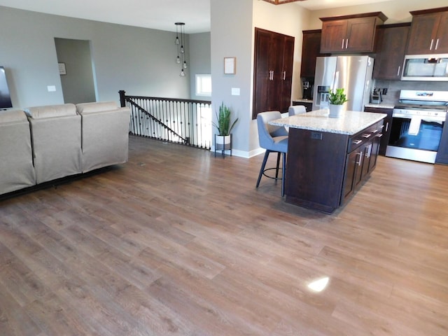 kitchen featuring light wood-type flooring, a breakfast bar, a kitchen island, open floor plan, and stainless steel appliances