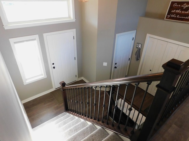 stairway with a high ceiling, wood finished floors, and baseboards