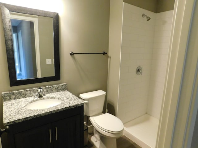 bathroom featuring tiled shower, toilet, and vanity