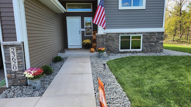 entrance to property featuring stone siding and a yard