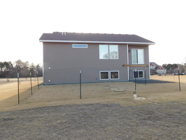 rear view of property with a lawn and fence