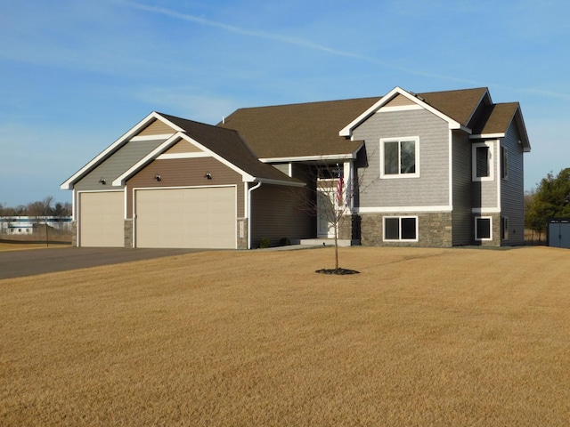 view of front of house featuring stone siding, an attached garage, and a front lawn