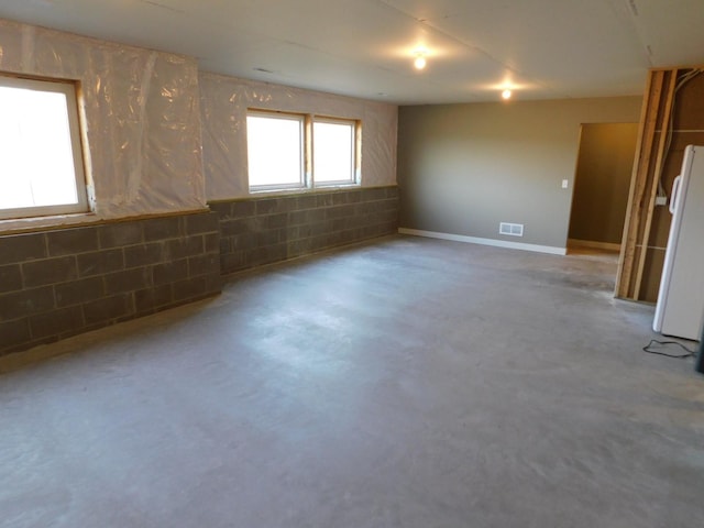 empty room with visible vents, concrete floors, and concrete block wall