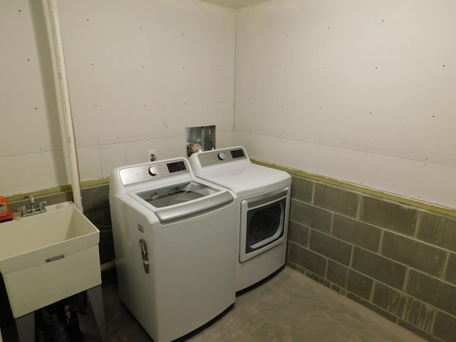 clothes washing area featuring laundry area, separate washer and dryer, and a sink