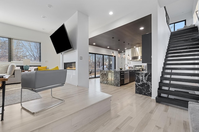 living area with recessed lighting, light wood-type flooring, plenty of natural light, and a glass covered fireplace