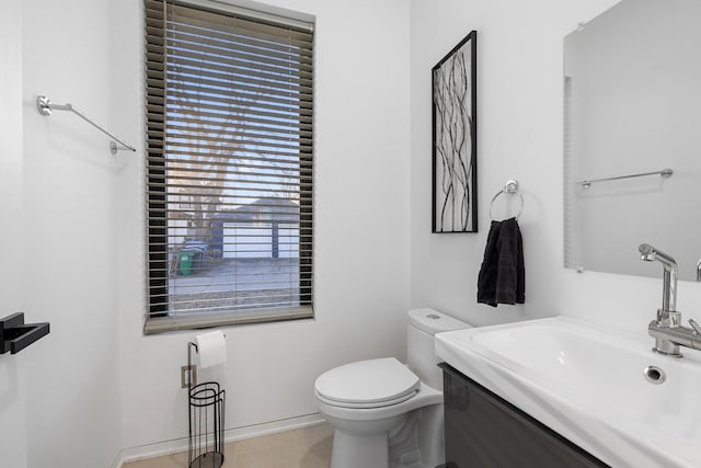 half bathroom with toilet, vanity, and baseboards