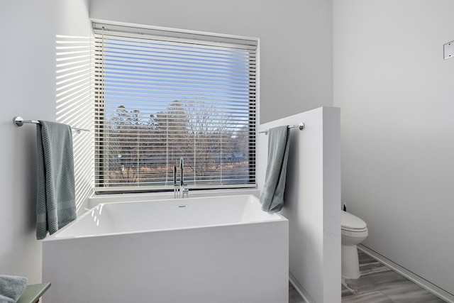 full bath with a freestanding tub, toilet, and wood finished floors