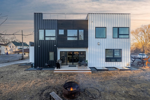 back of property featuring board and batten siding and an outdoor fire pit