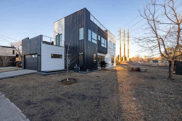 exterior space with central air condition unit, a balcony, concrete driveway, and board and batten siding