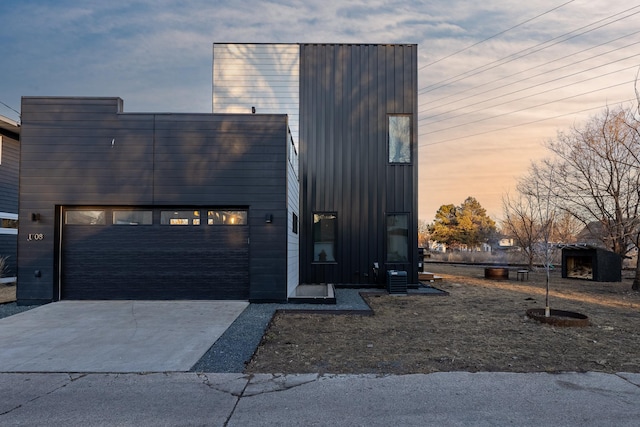 view of front of house with central air condition unit, concrete driveway, and a garage