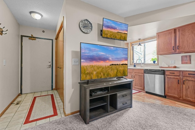 kitchen with dishwasher, light countertops, brown cabinets, a textured ceiling, and a sink