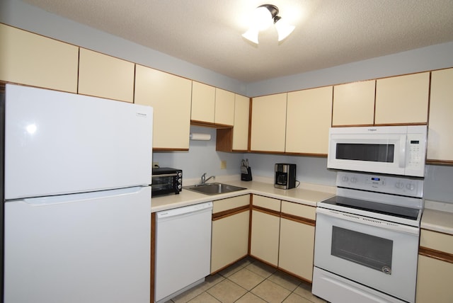 kitchen featuring white appliances, cream cabinets, light countertops, and a sink