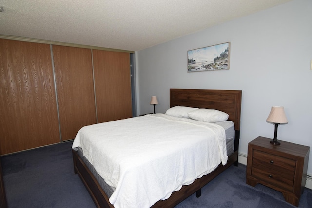 bedroom with a closet, carpet flooring, baseboard heating, and a textured ceiling