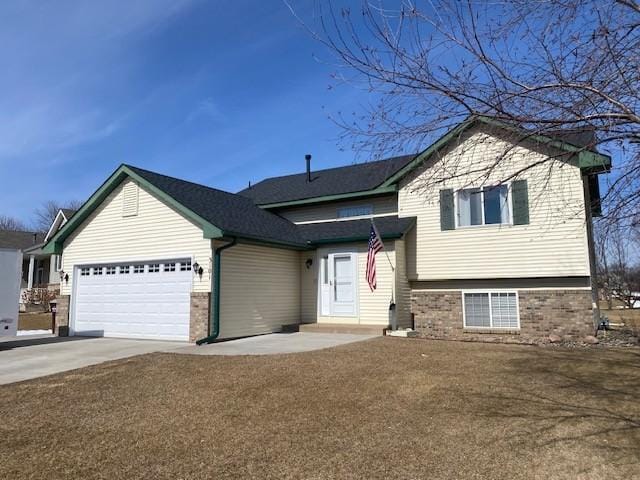 split level home with concrete driveway, an attached garage, and brick siding