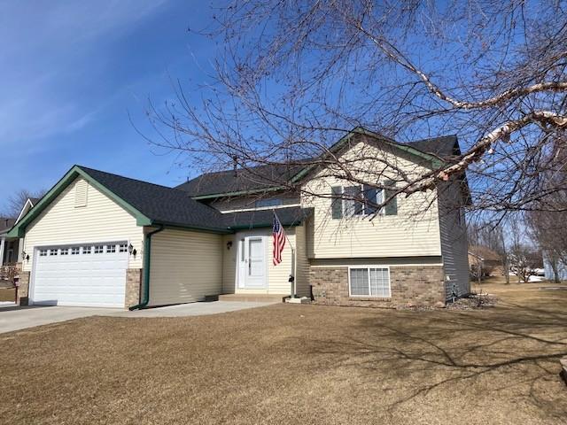 split level home with brick siding, an attached garage, and concrete driveway