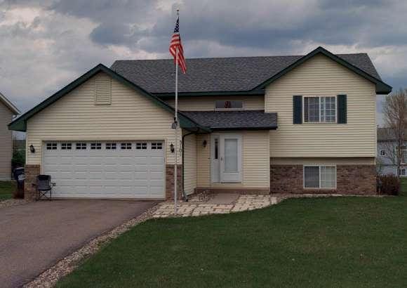 split level home with aphalt driveway, an attached garage, brick siding, and a front yard