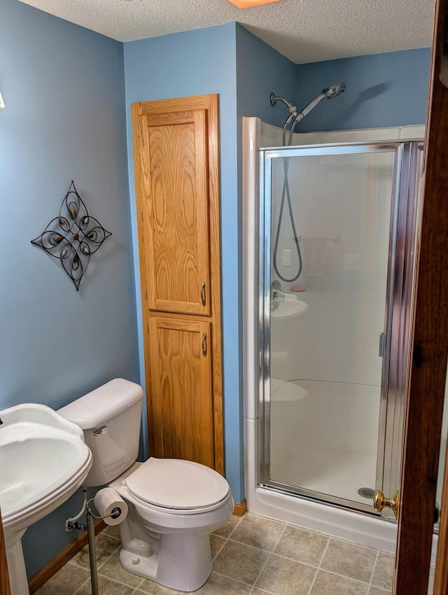 full bath featuring tile patterned flooring, a shower stall, toilet, and a textured ceiling