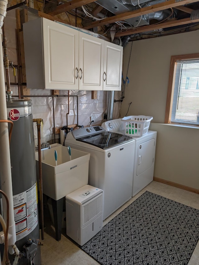 washroom featuring baseboards, washing machine and clothes dryer, cabinet space, a sink, and gas water heater