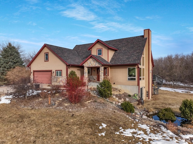 view of front of property featuring stone siding, a chimney, and a garage