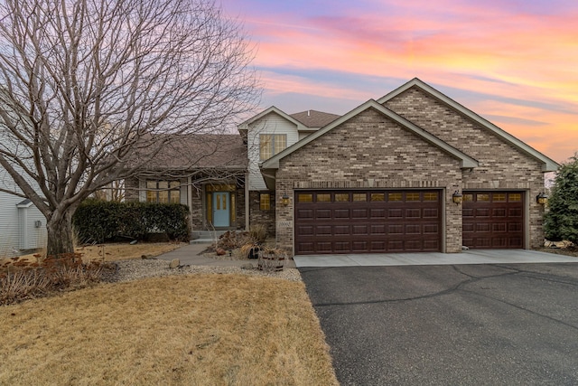 view of front of home featuring aphalt driveway, brick siding, and a garage