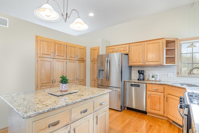 kitchen with light stone counters, backsplash, appliances with stainless steel finishes, and a sink