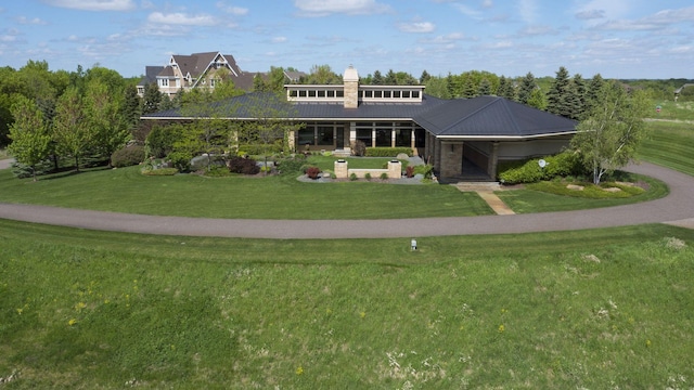 view of front facade with a chimney, metal roof, and a front lawn