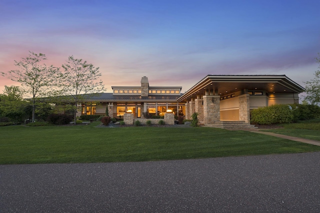 view of front of home featuring a front yard, a chimney, metal roof, stone siding, and a standing seam roof