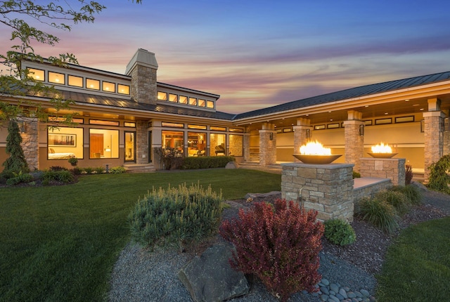 rear view of property with a standing seam roof, a lawn, and metal roof