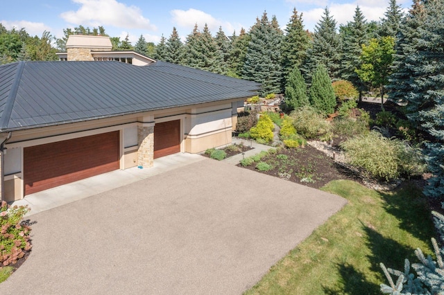 view of front of home with stone siding, an attached garage, and driveway