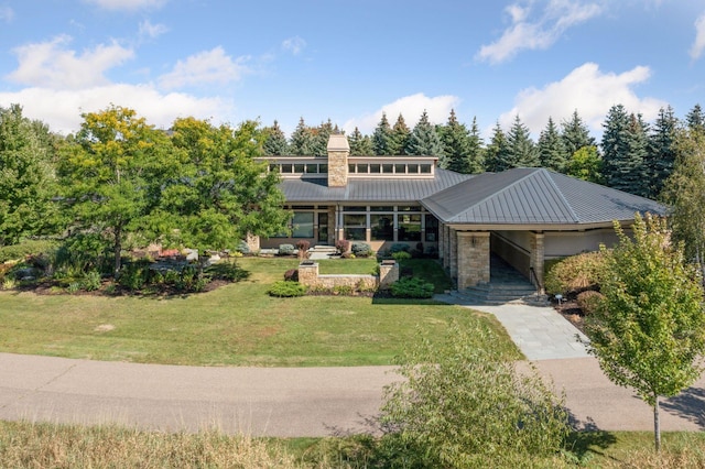 mid-century modern home featuring a standing seam roof, a front lawn, a chimney, and metal roof