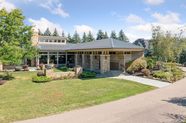 view of front facade with a standing seam roof, stone siding, metal roof, and a front lawn