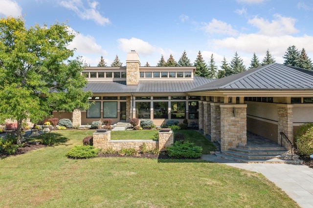 rear view of property featuring a yard, stone siding, metal roof, and a standing seam roof