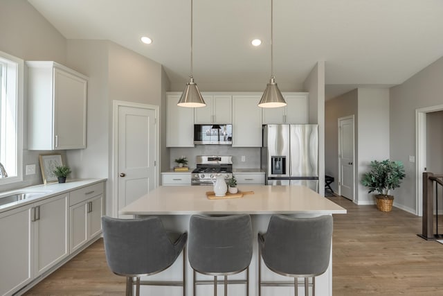 9176 62nd St S, Cottage Grove, MN 55016 - kitchen with stainless steel appliances, decorative backsplash, a breakfast bar area, a center island, and white cabinetry