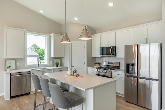 9176 62nd St S, Cottage Grove, MN 55016 - kitchen with appliances with stainless steel finishes, light wood-style floors, a kitchen island, lofted ceiling, and white cabinetry